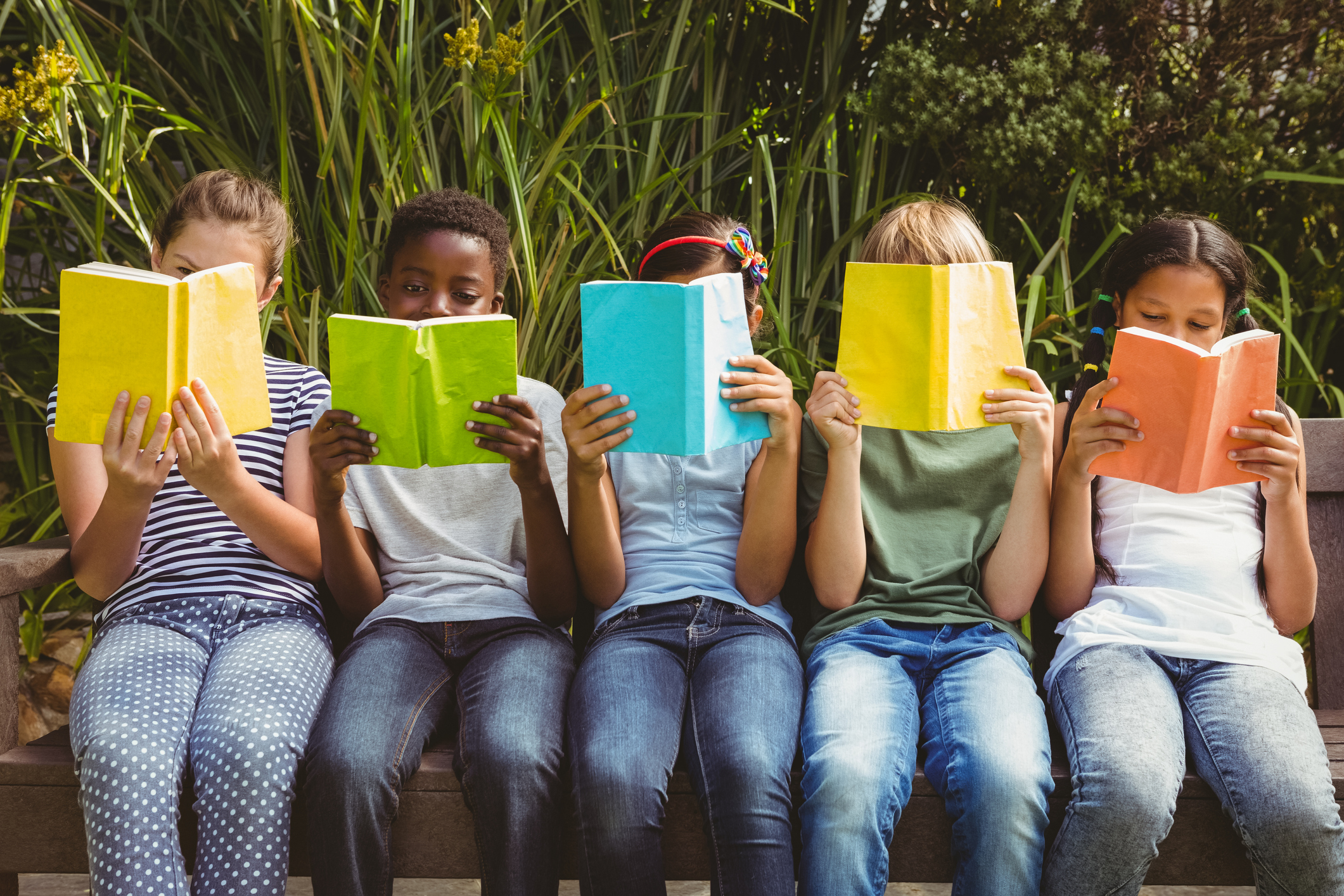 Children reading books that partially obscure their faces. 