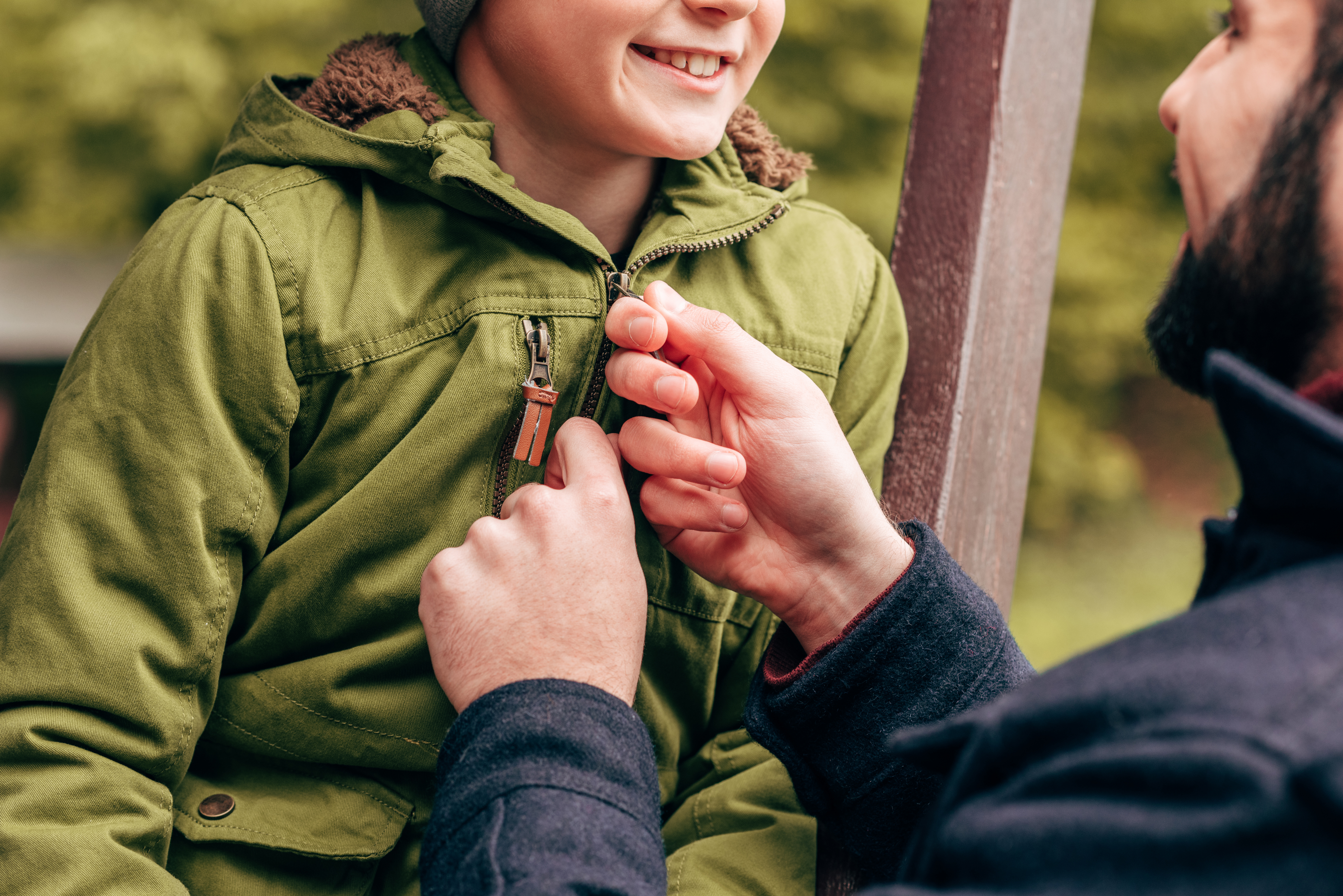 Man helps boy zip jacket.