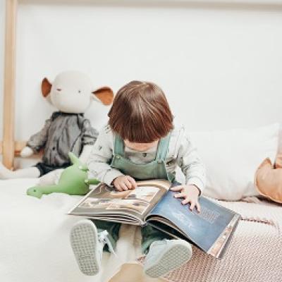 child reading wordless picture book while sitting on bed